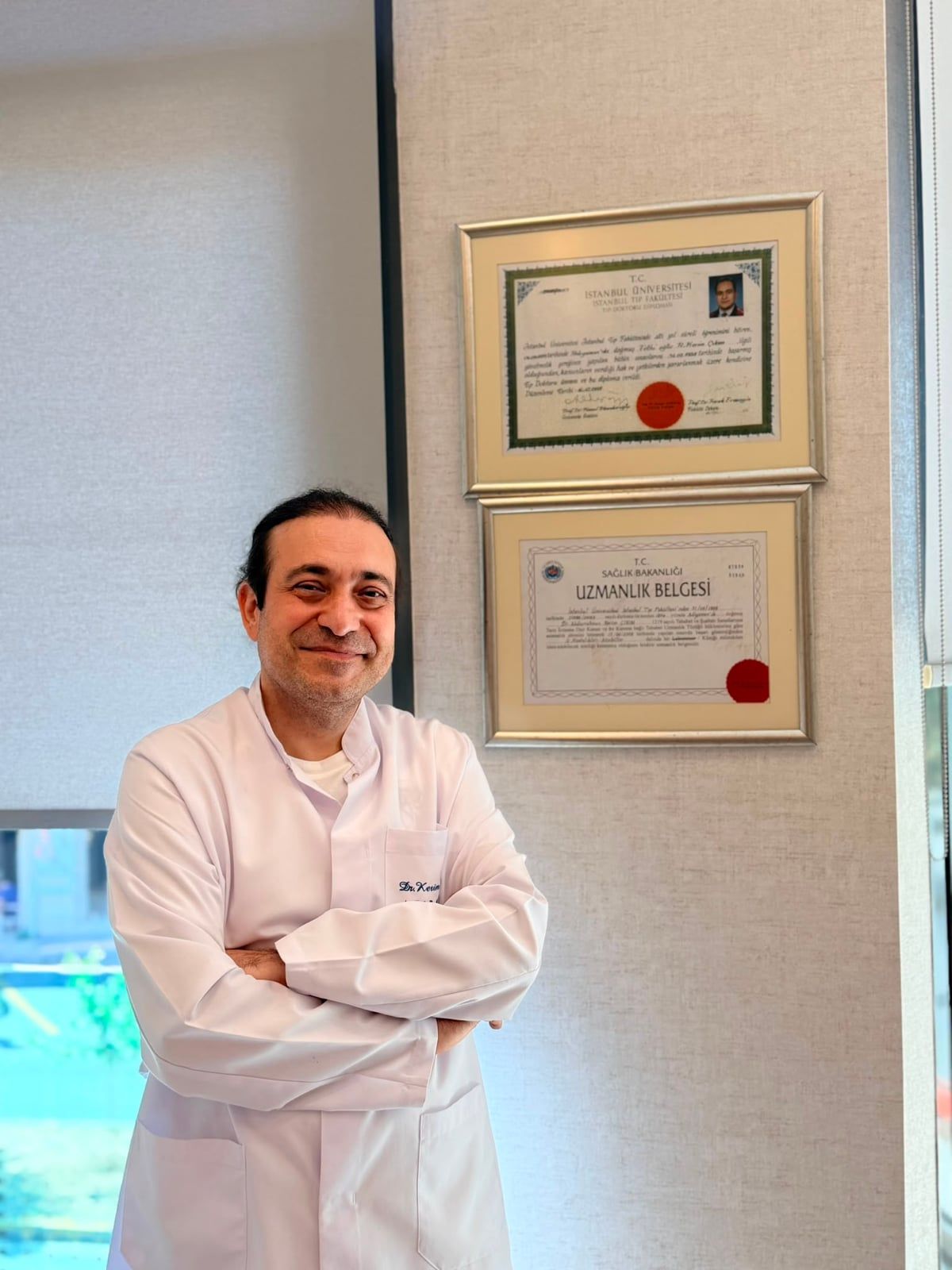 Uzm. Dr. Kerim Çıkım, diploması ve uzmanlık belgesinin önünde